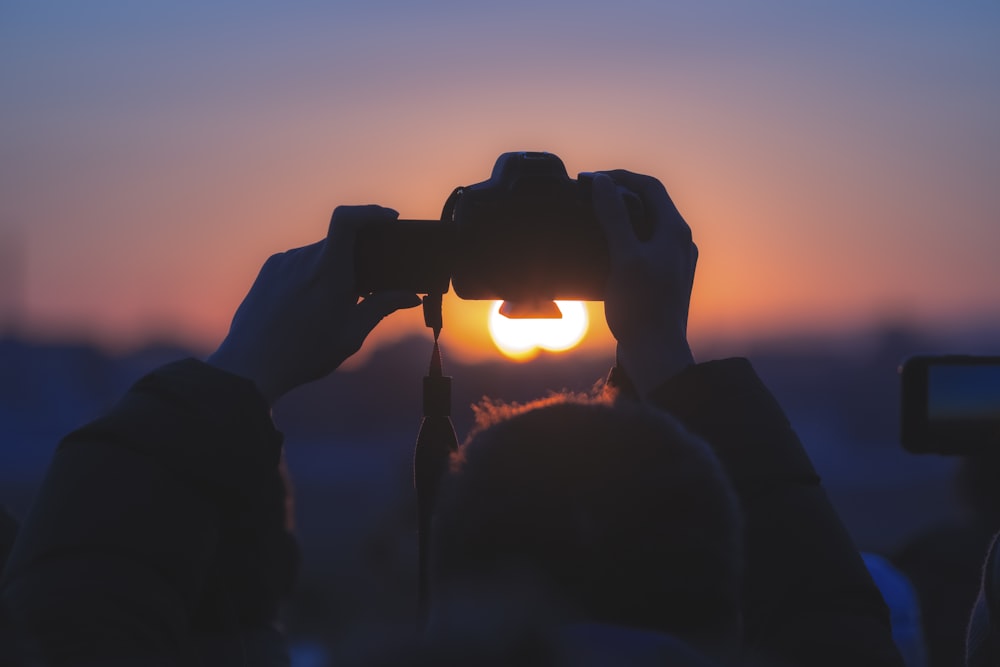 a person taking a picture of the sun through a pair of binoculars