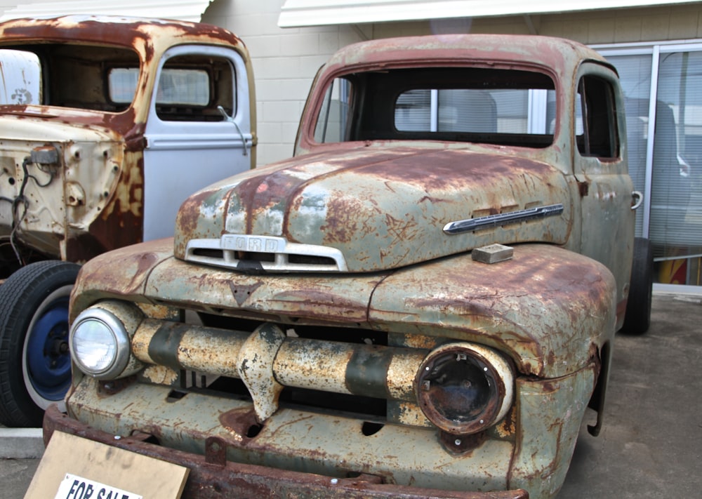 two old trucks parked next to each other in a parking lot