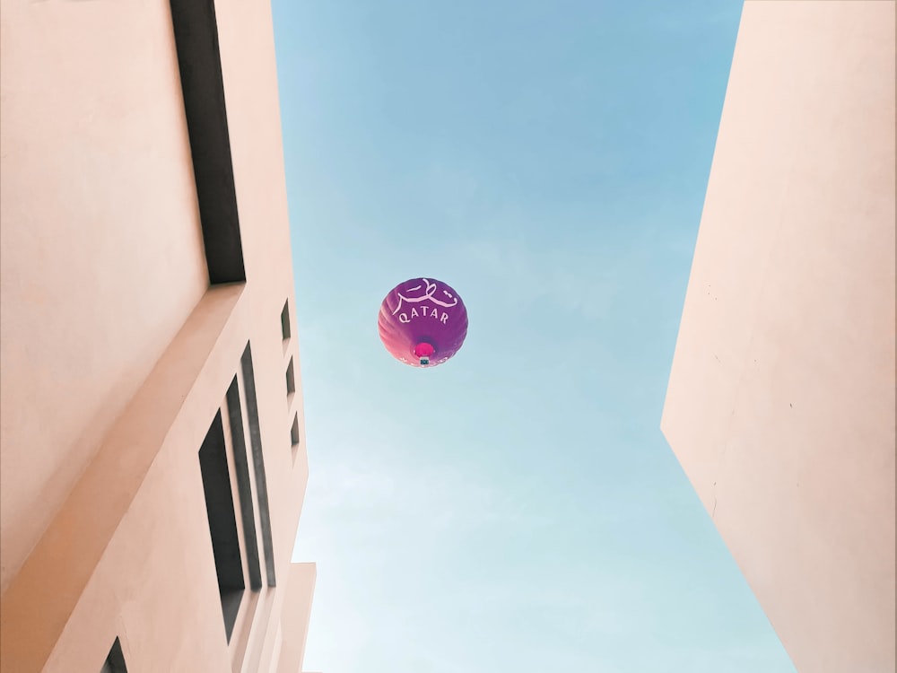 a purple balloon flying in the air between two buildings
