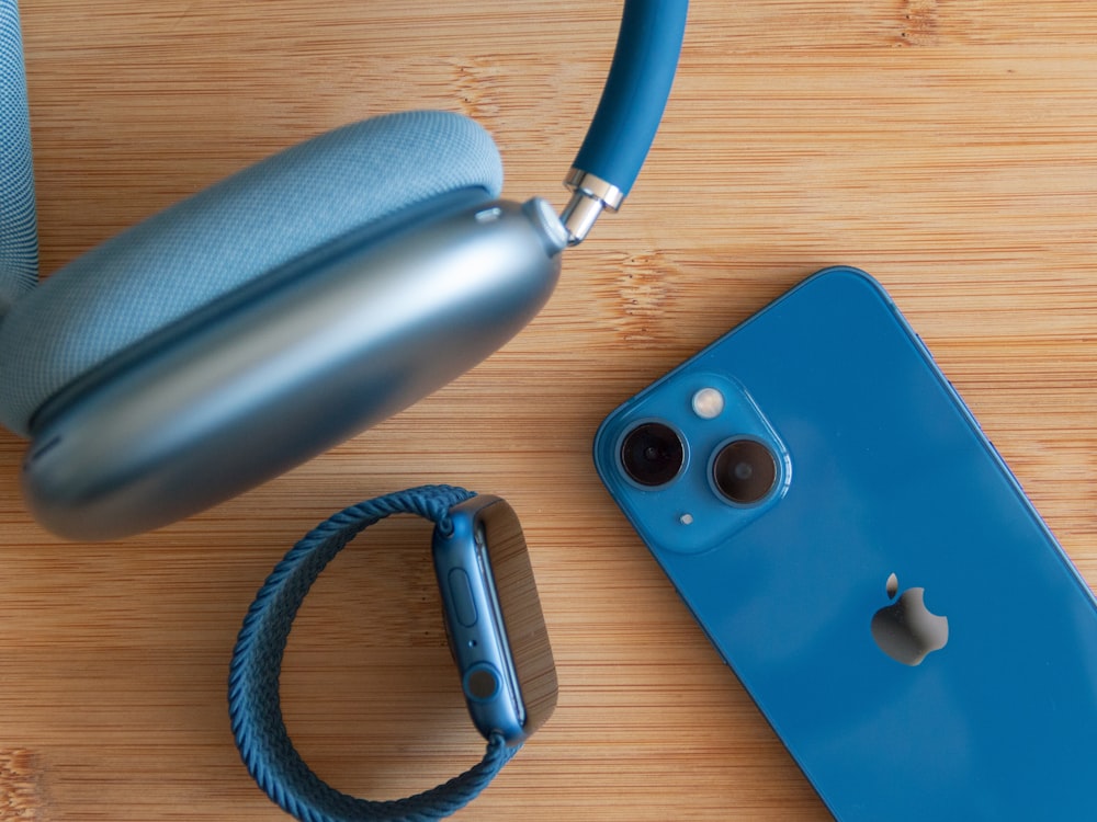 a pair of headphones and a blue iphone on a wooden surface