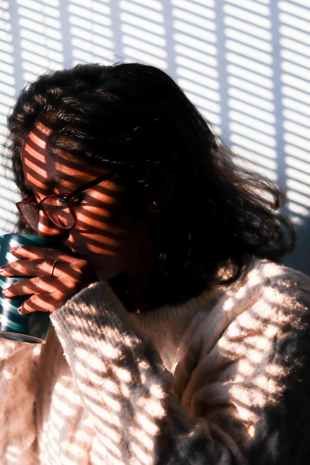 a woman with glasses holding a cup of coffee