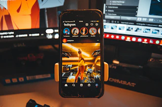 a cell phone is held up in front of a computer