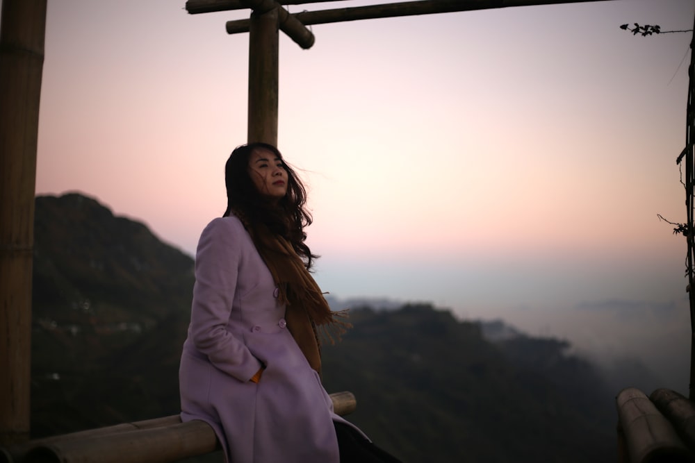 a woman in a purple coat standing on a balcony