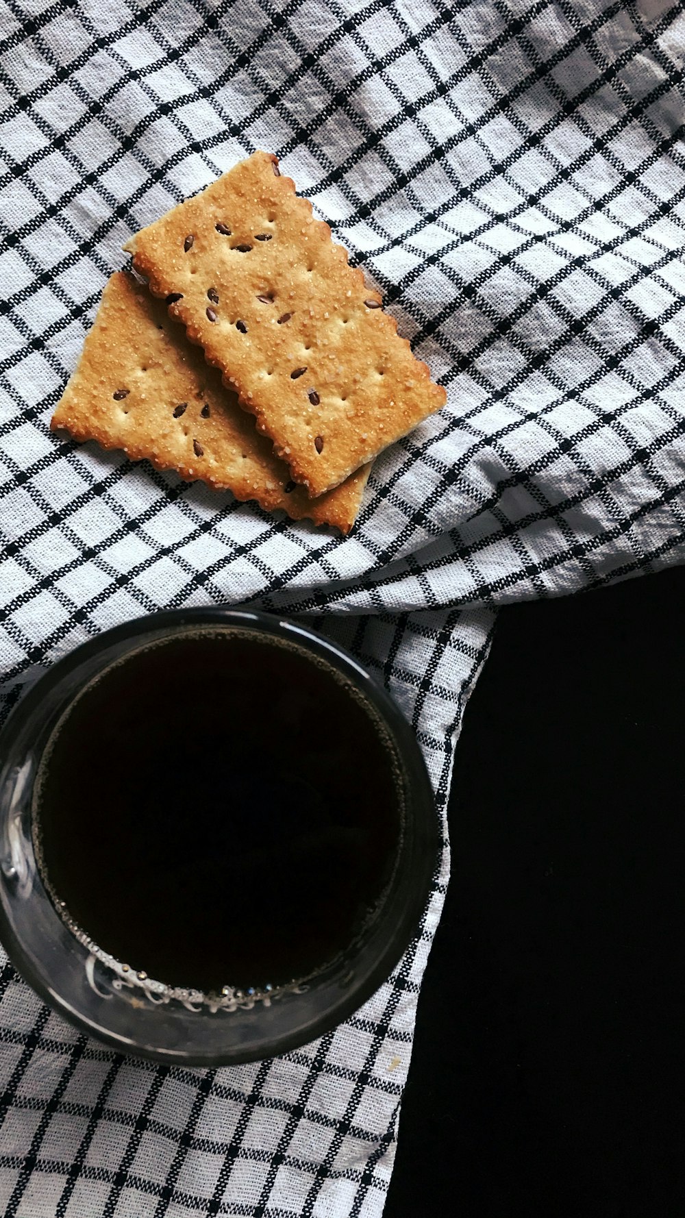 a cup of coffee and crackers on a table