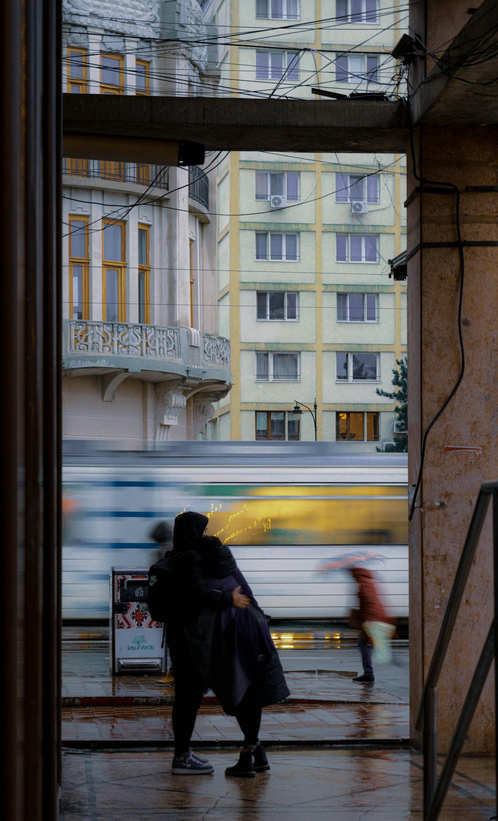 a person standing on a sidewalk in front of a train