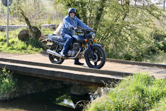Biker crossing a wooden bridge over a clear mountain stream in a peaceful rural setting