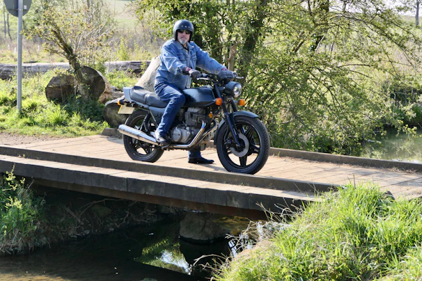 Biker crossing a wooden bridge over a clear mountain stream in a peaceful rural setting