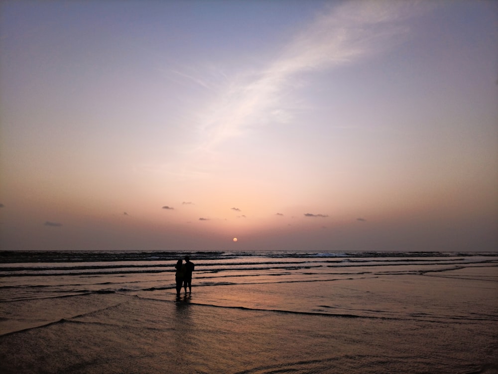 a couple of people standing on top of a beach