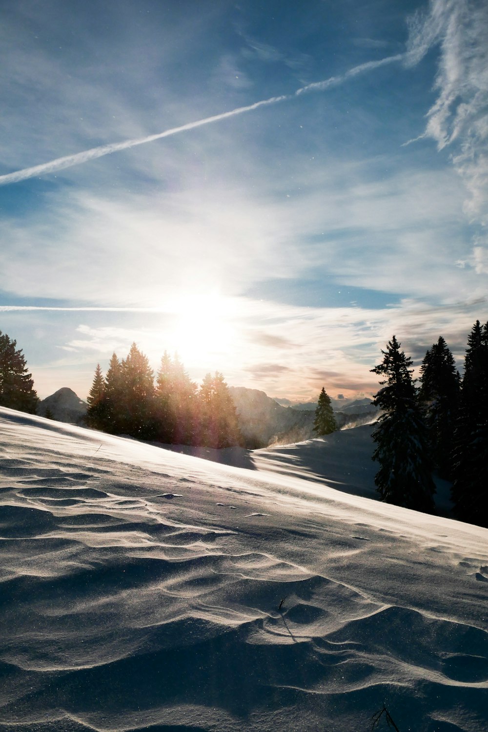 the sun is shining over a snow covered hill