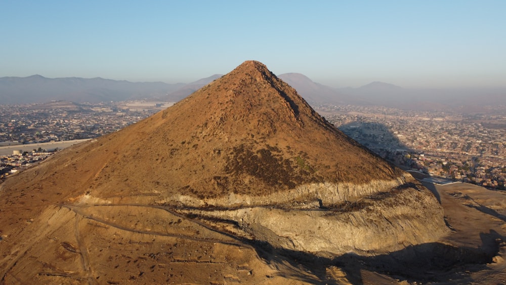 an aerial view of a mountain with a city in the background