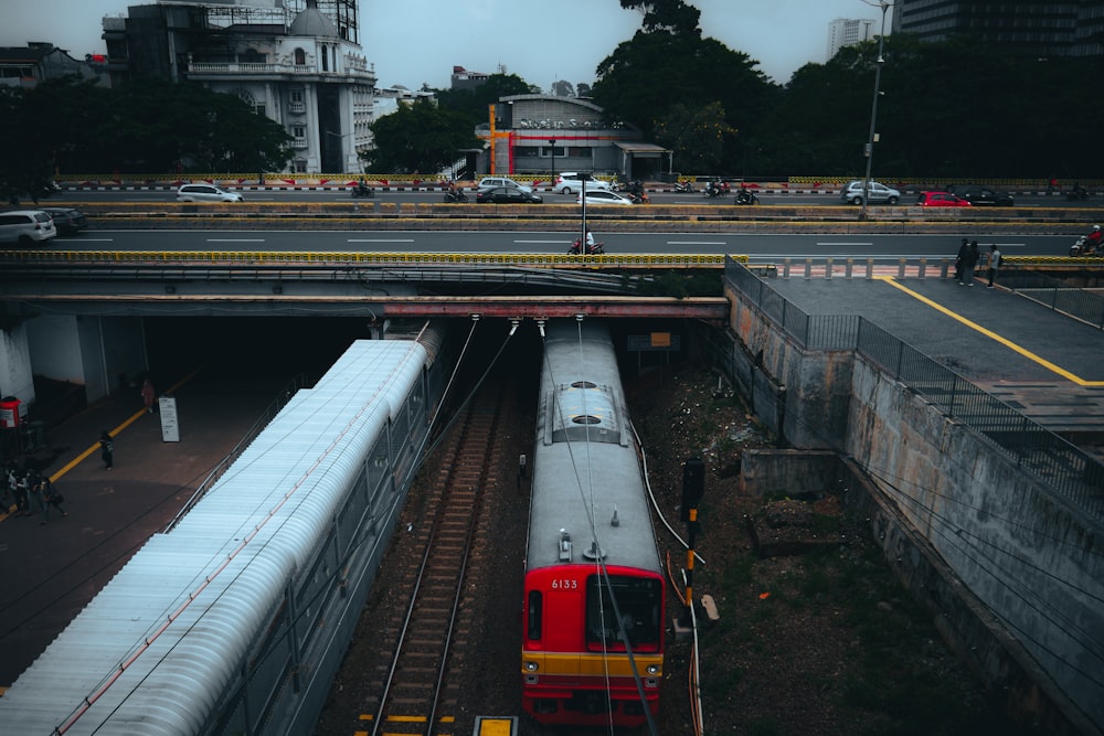 a red and white train passing under a bridge