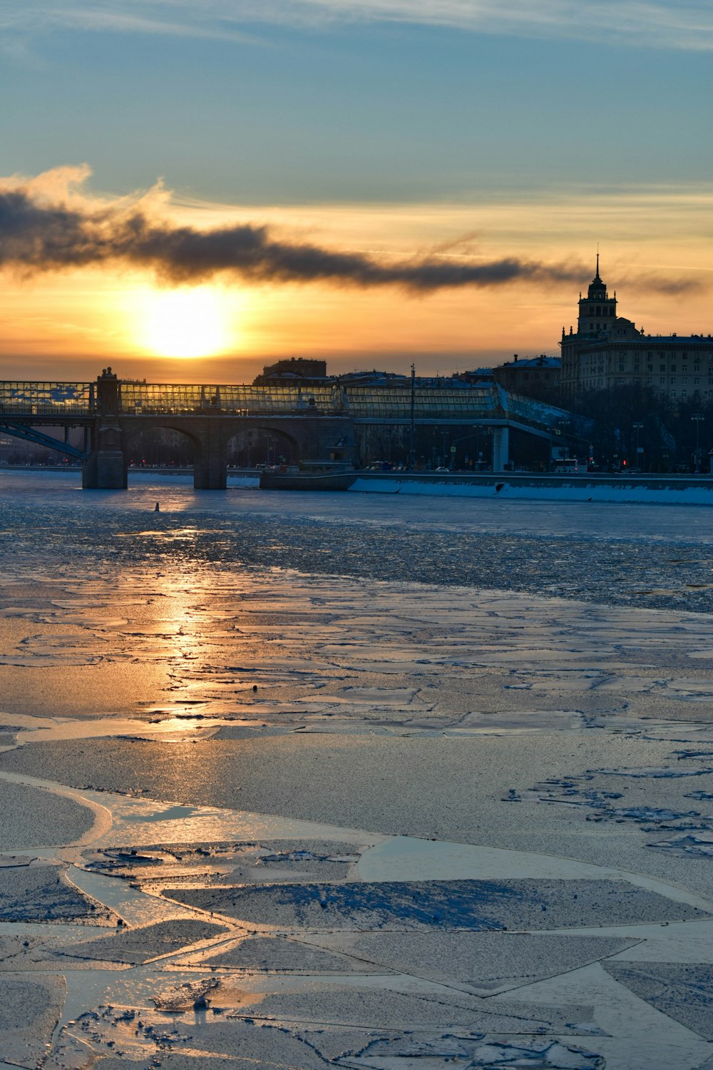 the sun is setting over a frozen river