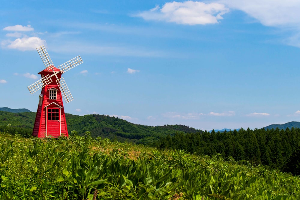 a red windmill in a field of tall grass