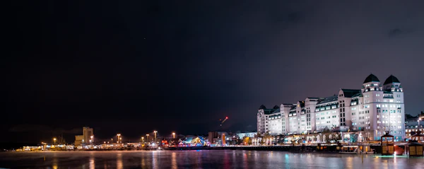The Oslo waterfront lit up at night, city lights reflected in the fjord — no aurora visible