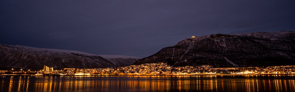 a night time view of a town on the shore of a lake