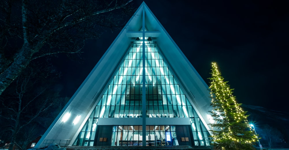 a church with a lit christmas tree in front of it