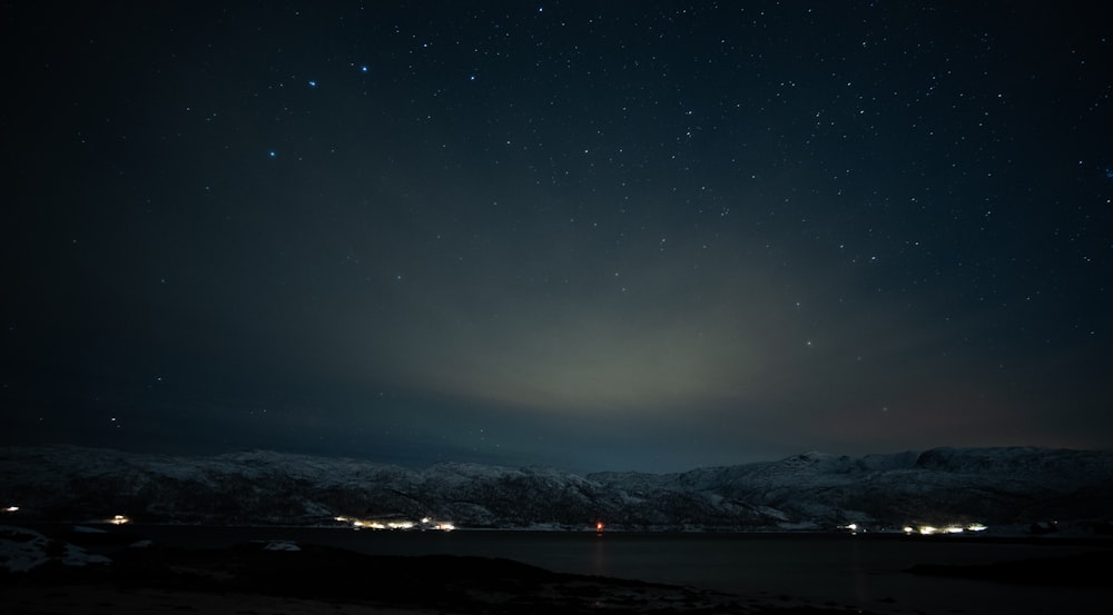 the night sky with stars above a body of water