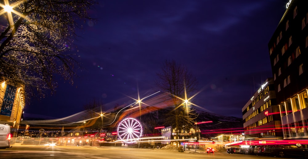 a city street at night with a ferris wheel