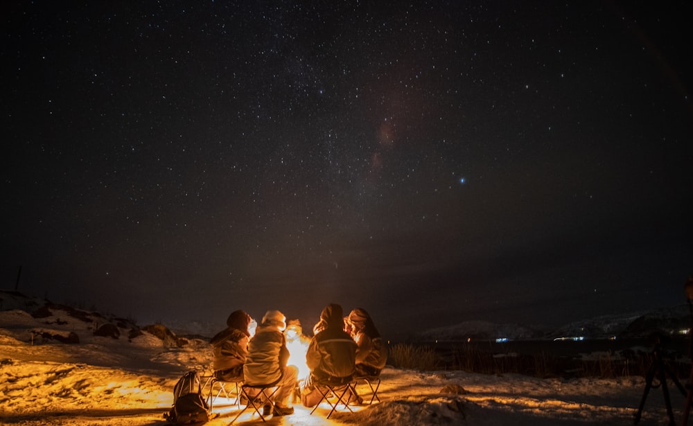 a group of people sitting around a campfire