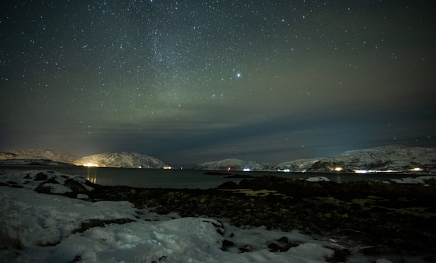the night sky with stars above a body of water