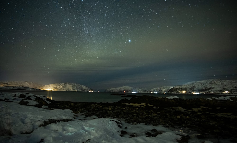 the night sky with stars above a body of water