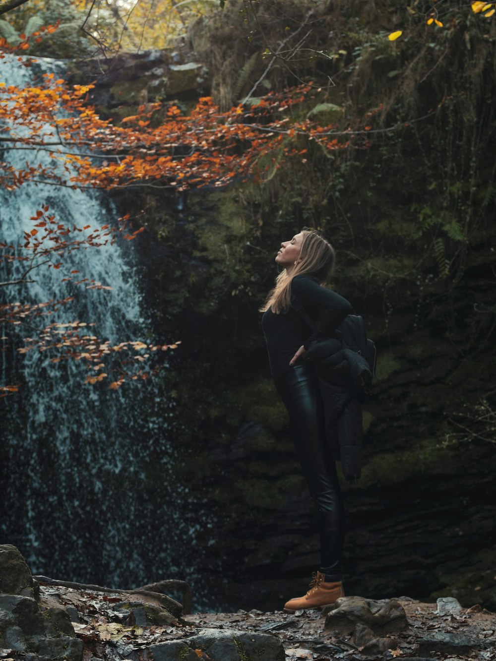 uma mulher em pé na frente de uma cachoeira