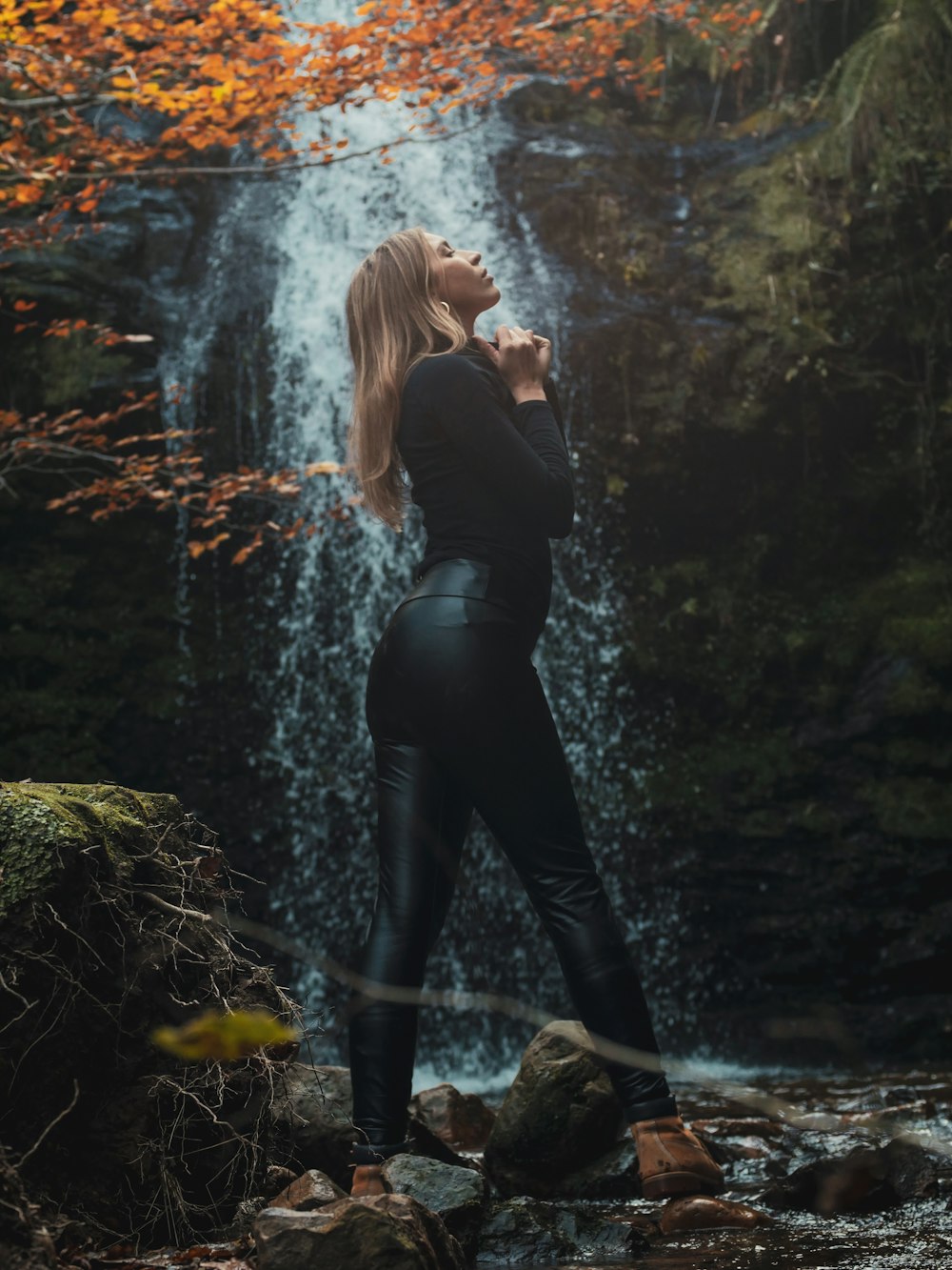 uma mulher em pé na frente de uma cachoeira