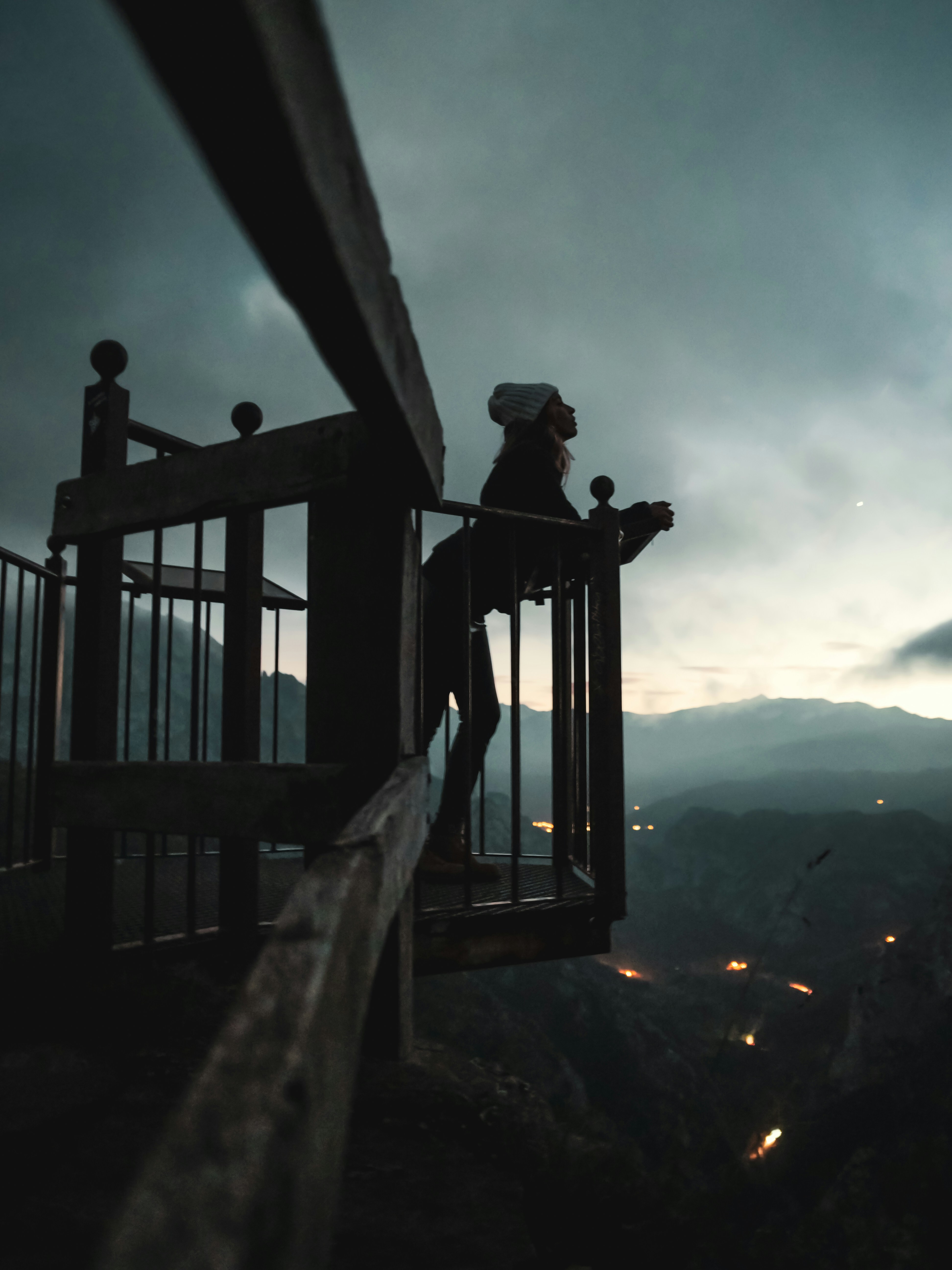 A person standing on top of a wooden railing photo – Free Night Image ...