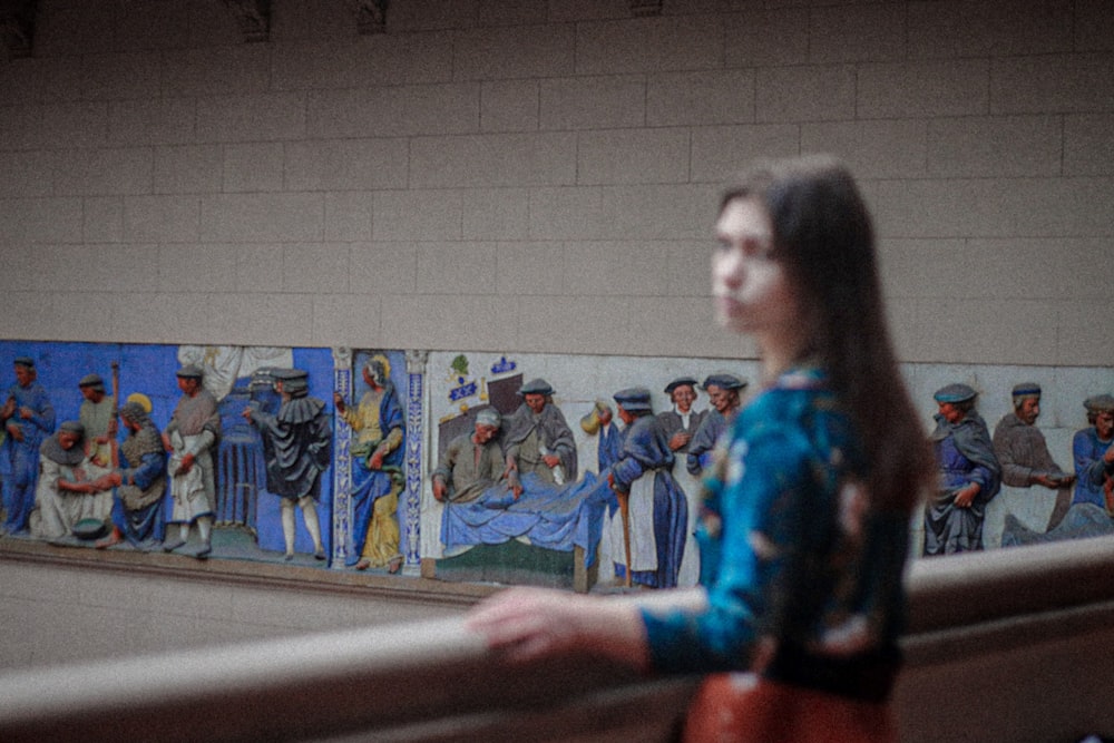 Una mujer parada frente a una pared con pinturas