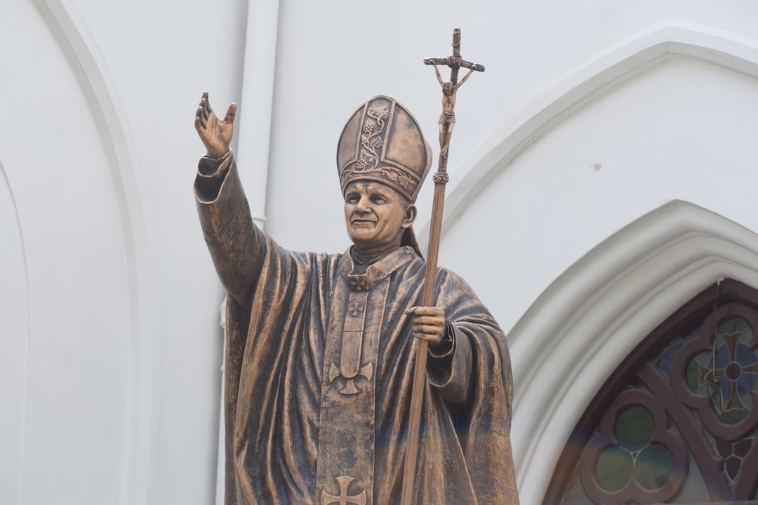 a statue of a man holding a cross in front of a church,
