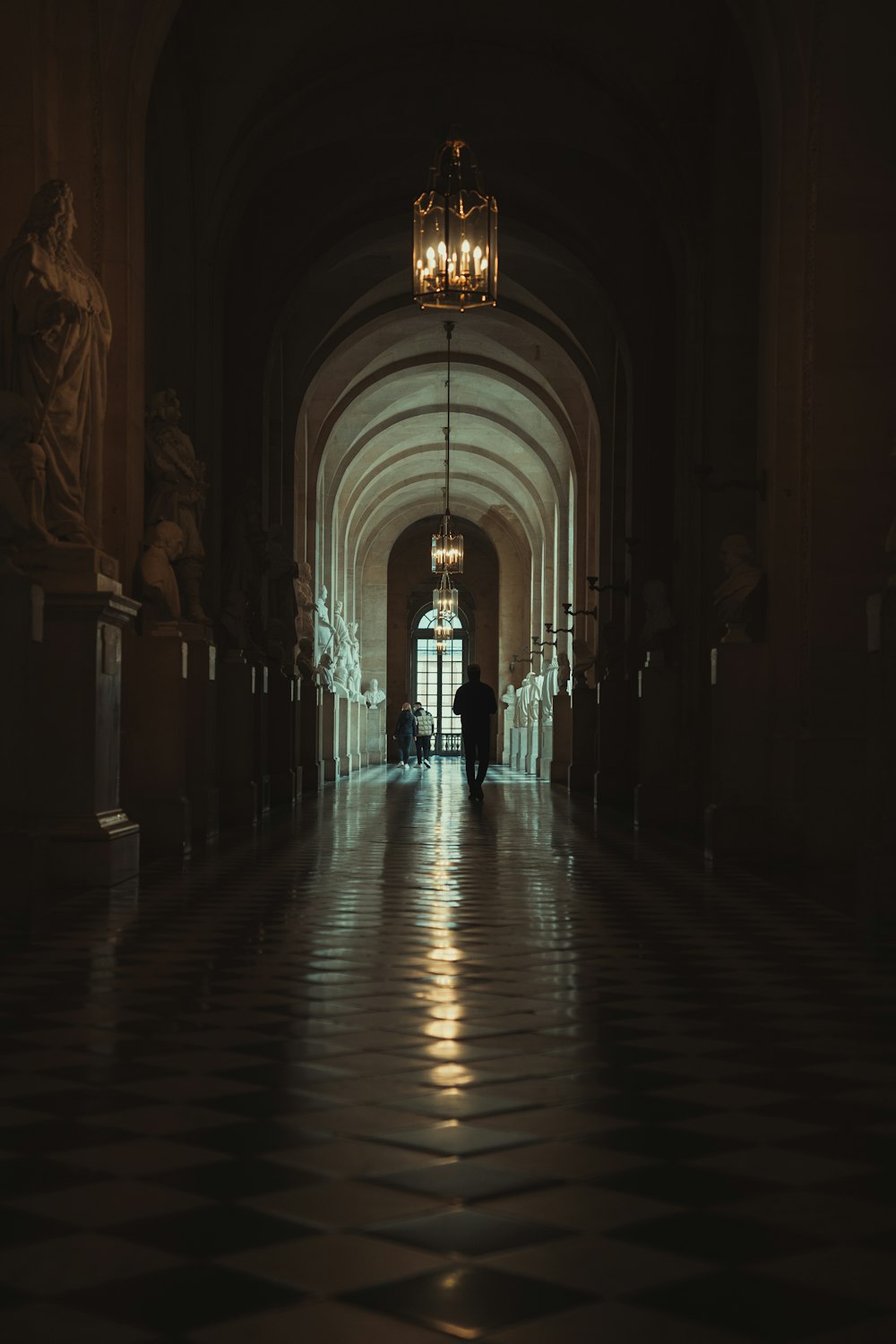 a hallway in a building with statues and a lamp