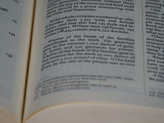 A close-up view of an open book with text focused on two columns. The text appears to be biblical or religious in nature, containing numbers and references to historical or religious events.