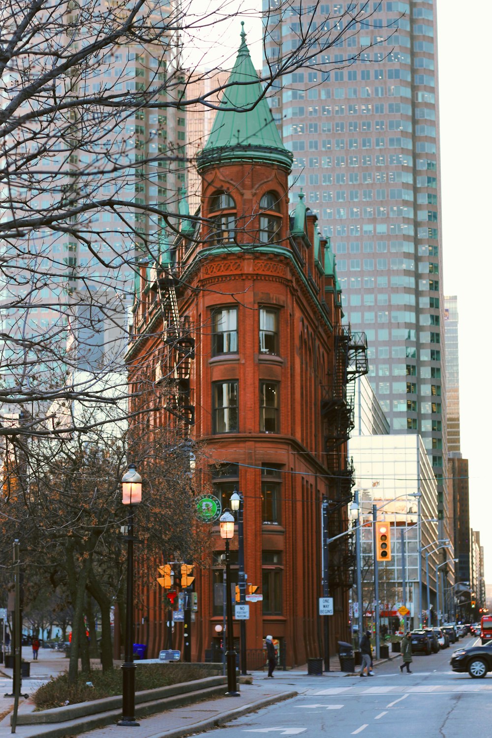 a tall red building with a green top on a city street