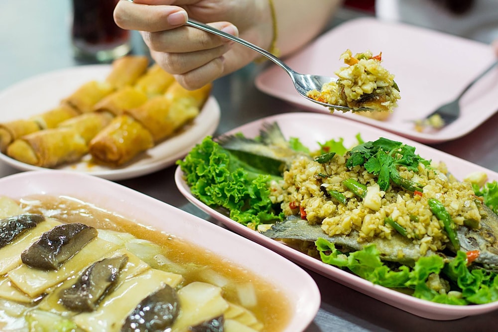 a person holding a spoon over a plate of food