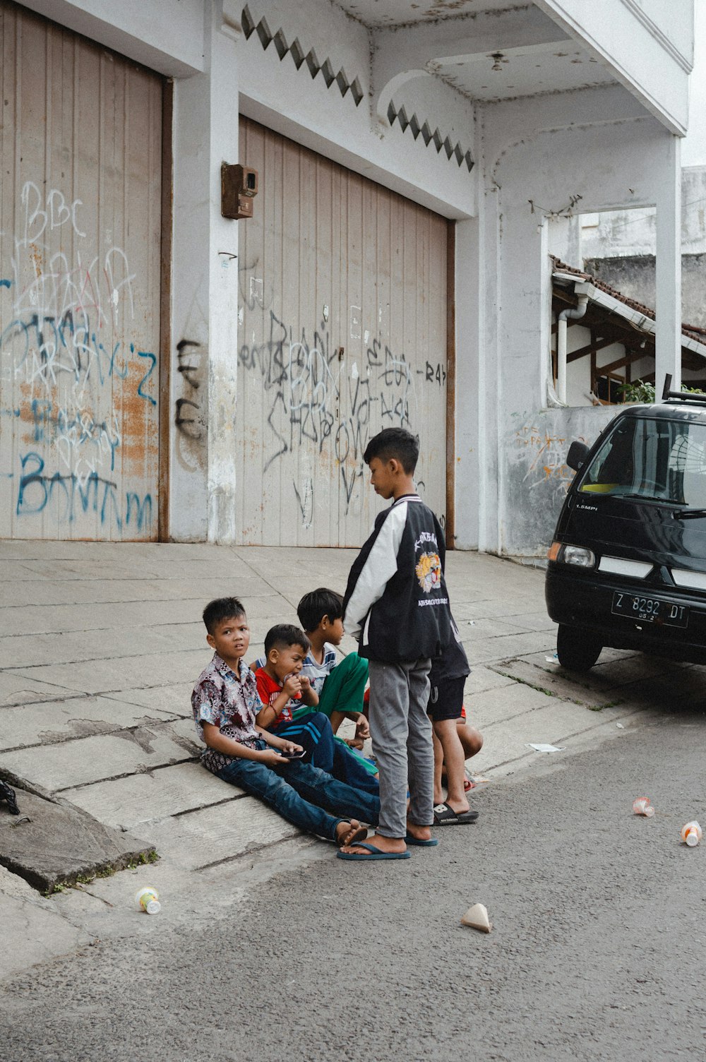 a group of young boys sitting on the side of a road