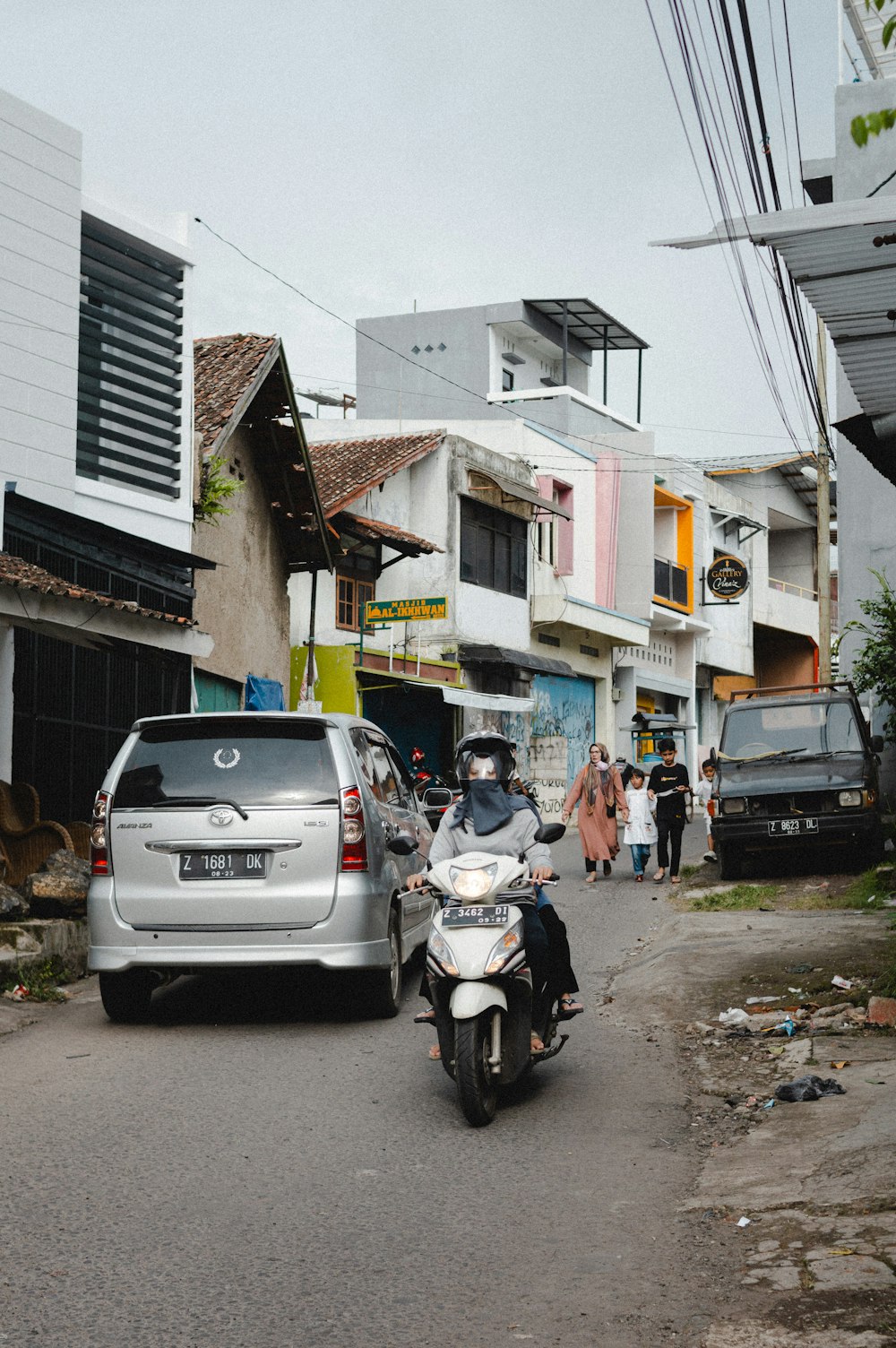 a man riding a motorcycle down a street next to a car