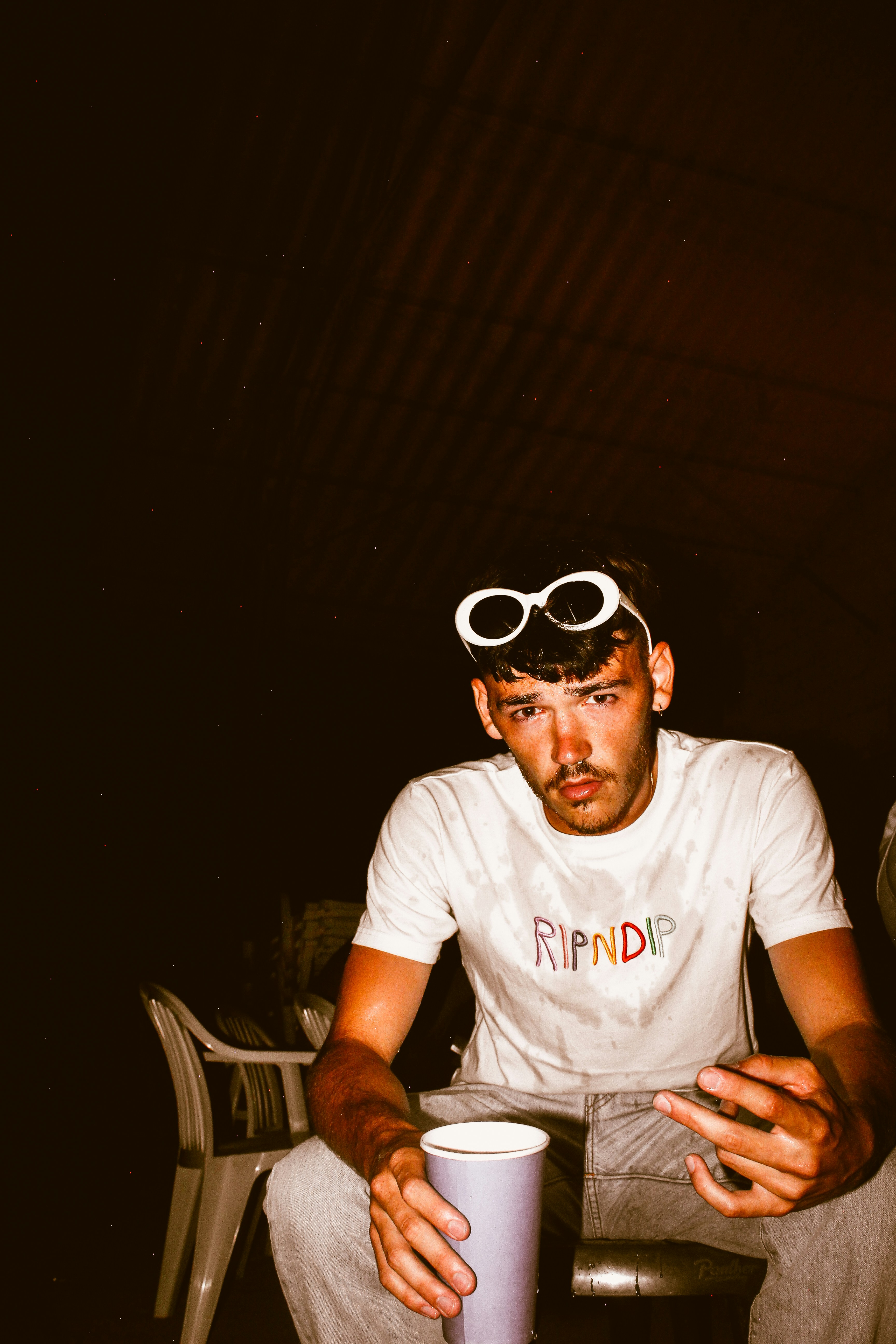 Un uomo seduto su una sedia che tiene una tazza di caffè