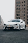 a white sports car parked in front of a tall building