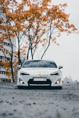 a white sports car parked in front of a tree