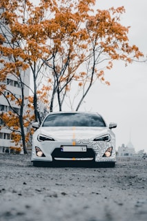 a white sports car parked in front of a tree