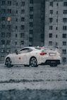 a white car parked in front of a tall building