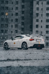 a white car parked in front of a tall building