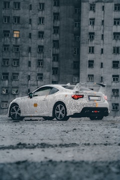 a white car parked in front of a tall building