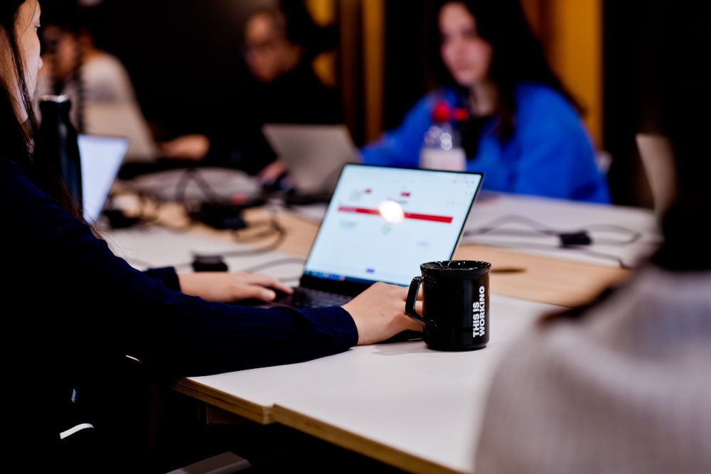 a group of people sitting at a table with laptops