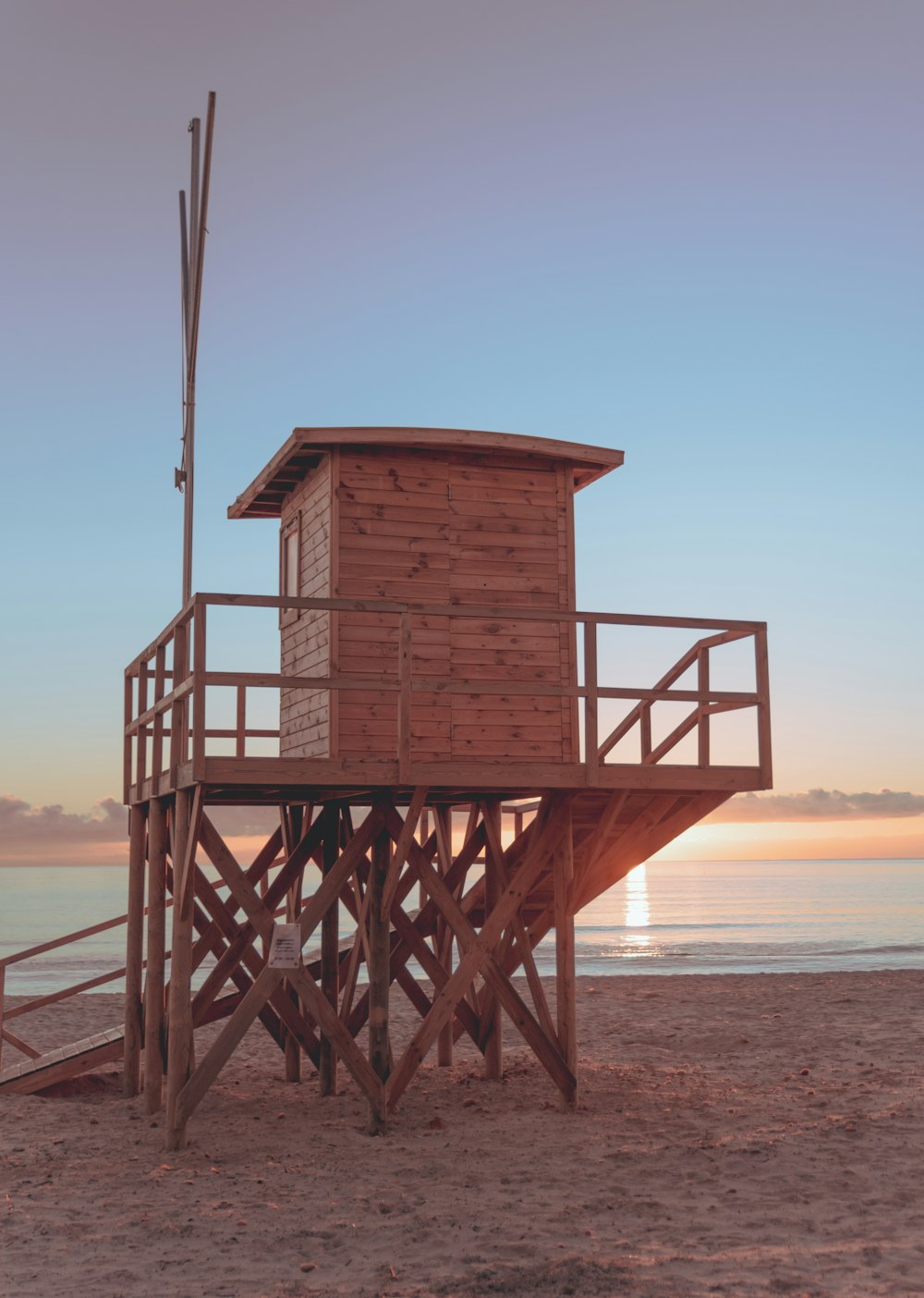 a lifeguard tower on the beach at sunset