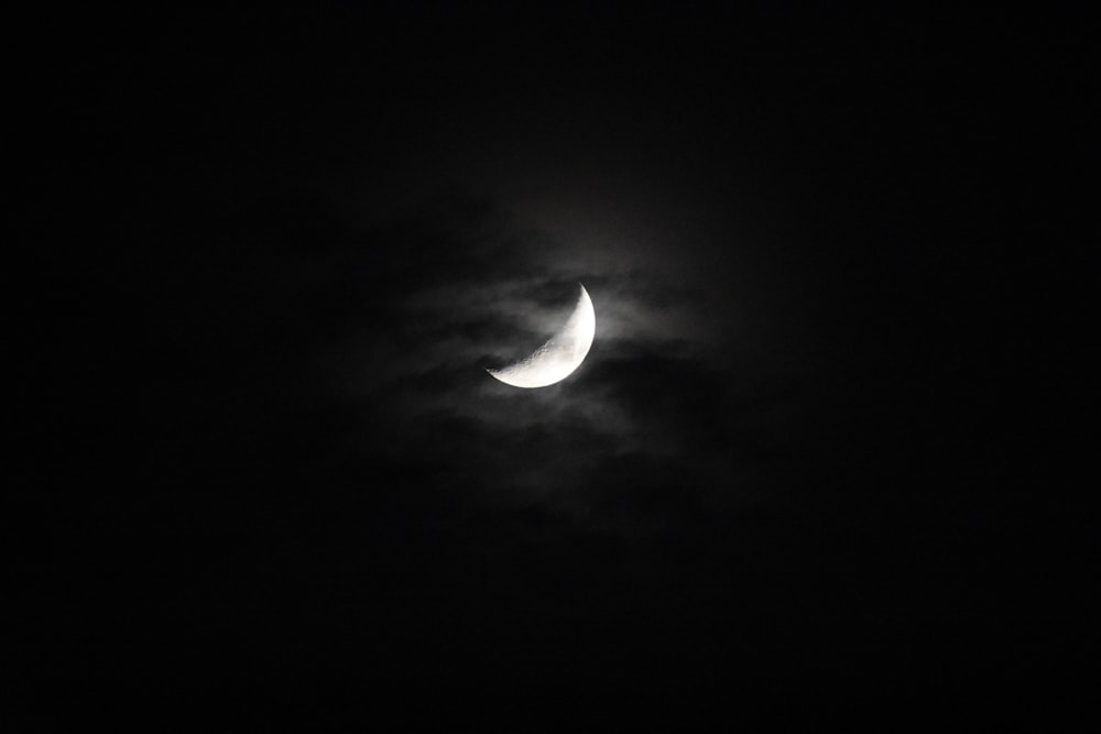 the moon is seen through the clouds in a dark sky