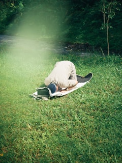 a man laying on top of a surfboard on top of a lush green field