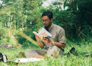 Young man reading book near river