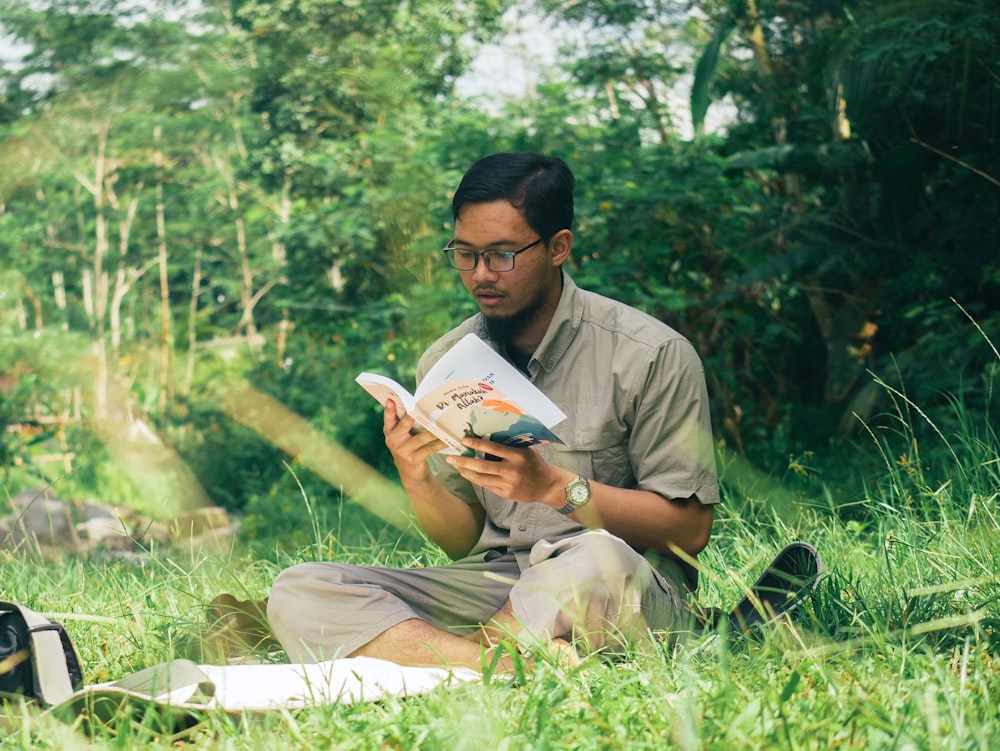 Un hombre sentado en la hierba leyendo un libro