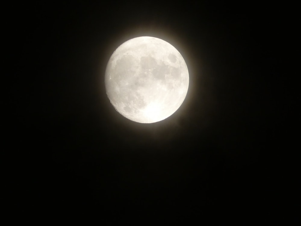 a full moon seen through the dark sky